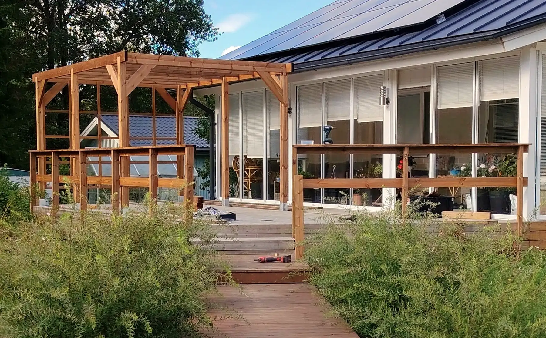 Puinen pergola ja terassi omakotitalon pihalla